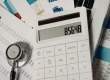 Healthcare billing paperwork and calculator showing medical billing cost