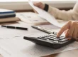 Person using a calculator to review financial documents.