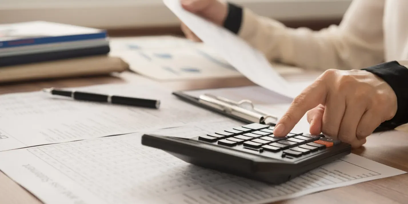 Person using a calculator to review financial documents.
