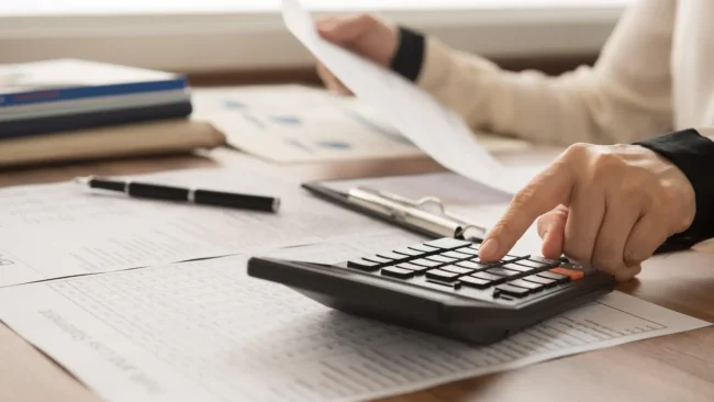 Person using a calculator to review financial documents.