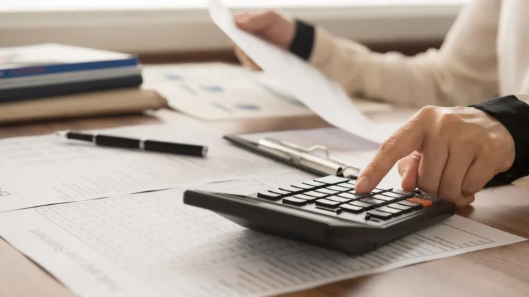 Person using a calculator to review financial documents.